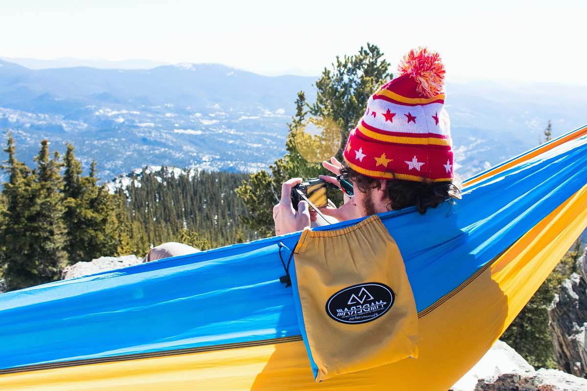 hat man in red and white bobble knit cap on blue and yellow hammock chief mountain